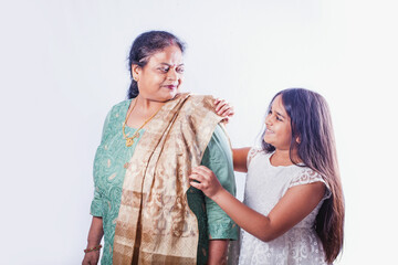Cute Indian little girl helping her grandmother wear a dupatta