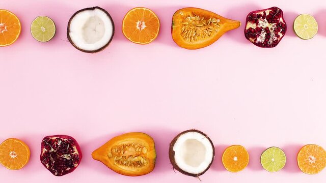 Slices of ripe fruits move left and right on top and bottom of pastel pink theme. Stop motion 