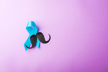 Black mustache paper and light blue ribbon, studio shot isolated on purple background, Prostate...