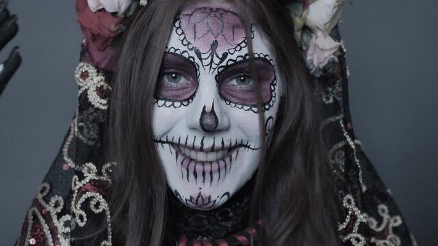 Halloween makeup, Santa Muerte or sugar mexican skull, makeup. The girl closes and opens her face with different grimmas. Slow motion