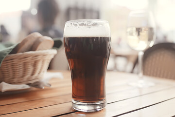 mug of dark beer in the interior of  pub / pint of beer with foam on a served table in  beer restaurant in Czech Republic