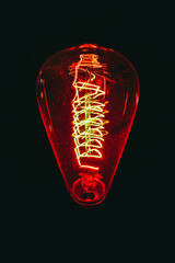 Incandescent electric light globe hang on the ceiling isolated on black background.