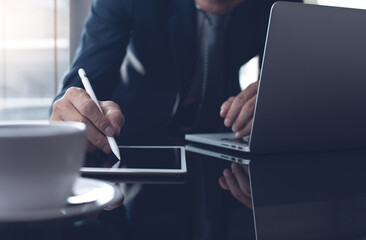 Businessman manager using stylus pen signing business document on digital tablet working on laptop computer in office