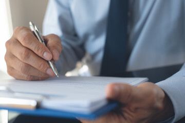 Businessman with pen in hand signing business document working in office