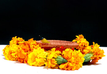Marigold flowers around Clay Oil Lamp or Diwali Diya, over white background. selective focus