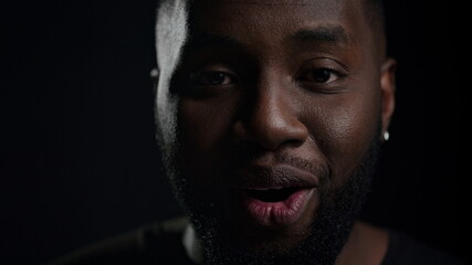 Fototapeta premium Euphoric afro guy posing indoors. African man saying wow on black background