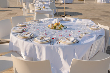 party reception table decorated with flowers: plates, forks, knives and wine glasses.