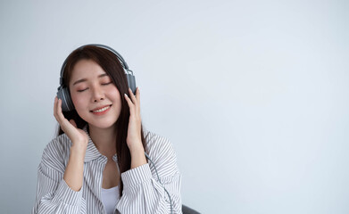 Fototapeta premium Beautiful and lovely Asian women wear headphones to listen to the music they like, their faces are very happy. Copy space and white background.
