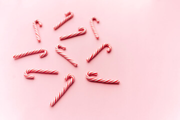 Top view of Christmas candy canes on pastel pink background. Holiday festive celebration greeting card with copy space to addng text