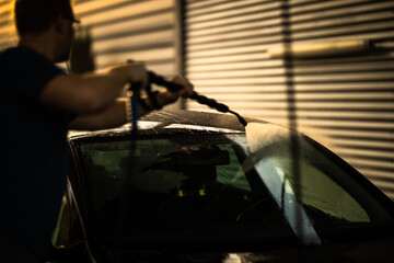 Young man washing his beloved car carefully in a manual car wash to prevent any damage and detail it properly