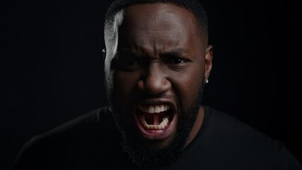 Wicked afro guy screaming on black background. Closeup man yelling in studio