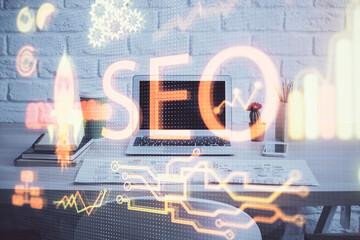 Multi exposure of table with computer and seo drawing hologram. Search optimization concept.