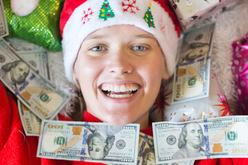 Happy woman covered by many 100 USD cash money bills and surrounded by presents on Christmas holidays.