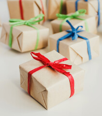 Pile of presents little boxes made from craft paper with colored ribbons on white background