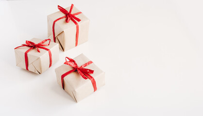 Gift boxes made from craft paper with red ribbon on white background with space for text.