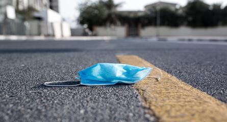Littering and pollution. Used face mask left discarded in city street.
