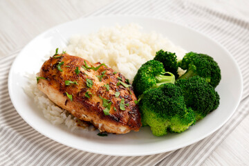 Homemade Chicken Breast, Rice and Broccoli on a white plate on a white wooden background, low angle view. Close-up.