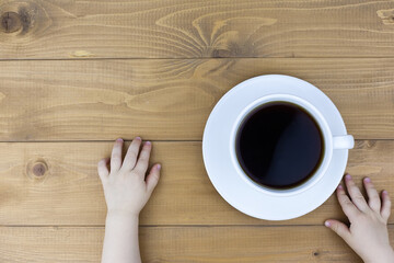 Woman's hands in sweater holding cup of coffee on the black wooden table