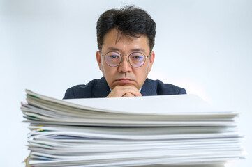 Documents or reports stacked with Asian middle-aged male businessman.