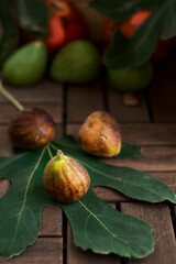 Autumn harvest.Close-up of pale figs on a fig tree leaf, set against a dark wooden background. Food delivery to the consumer. Selective focus, copy space