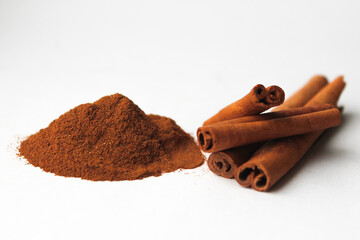 Loose cinnamon and cinnamon sticks on a white background. Cinnamon is used primarily for spices, imparting a spicy aroma to foods