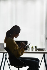 Portrait of businesswoman using digital tablet while relaxing in modern office room.
