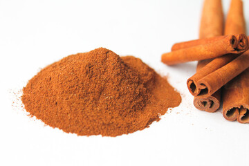 Loose cinnamon and cinnamon sticks on a white background. Cinnamon is used primarily for spices, imparting a spicy aroma to foods
