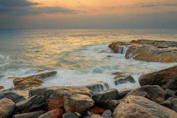 Rocks and stones at the ocean coast under a beautiful sunset sky with clouds on Sri Lanka island.