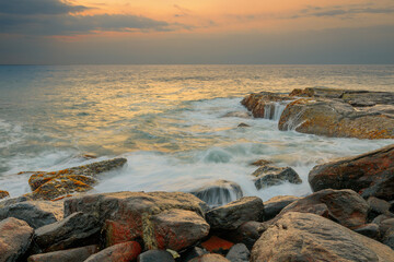 Obraz premium Rocks and stones at the ocean coast under a beautiful sunset sky with clouds on Sri Lanka island.