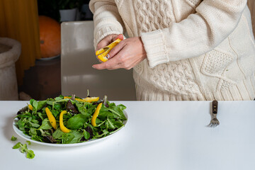 middle aged blonde woman preparing green salad in the kitchen, close-up
