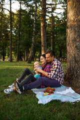 Mother, father and baby sitting under the tree