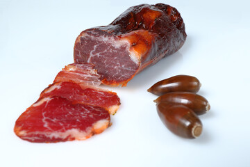 Acorn-fed Iberian loin with three slices cut, garnished with three acorns and with a white background