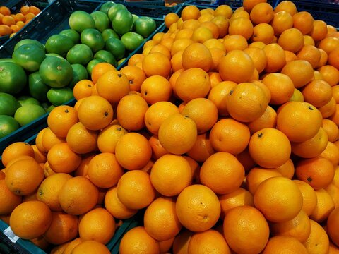 Organic and fresh oranges on fruit market, close up. Boxes full of ripe oranges for sale on farmers market. Fresh fruit display in shop.