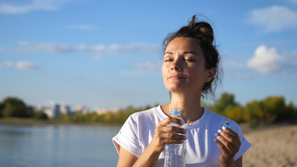 Freedom cheerful Girl with closed eyes holds bottle of the water on a hot sunny day. Healthy lifestyle.