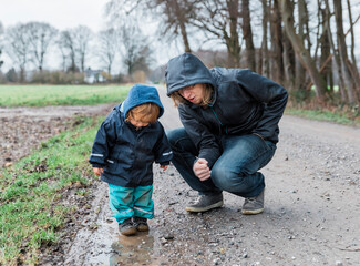 Toddler girl with young man crouching on footpath
