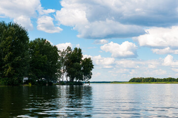 beautiful landscape of water and river coast with trees under blue sky with white clouds