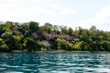 beautiful landscape of water with reflactions, hills covered with trees and blue sky with clouds on summer river