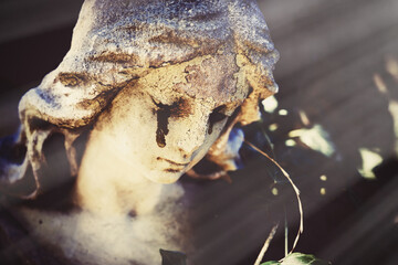 Fragment of ancient statue of crying angel with tears in face as symbol of end of human life. Close up. Selective focus on eyes.
