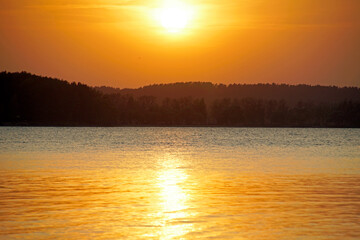 Warm summer evening. Landscape. Horizontal shot. Colorful sky before sunset. Bright glare on the surface of the water.	