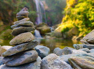 Stone pyramid near a tropical waterfall. The concept of harmony and balance. Stone Stacking or Stone Balancing.