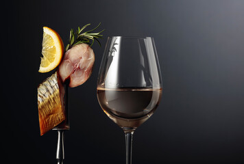 Glass of white wine and smoked mackerel with lemon slice.