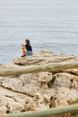 Woman sitting on rocks looking to the ocean