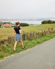 Girl walking beside the grass near the ocean