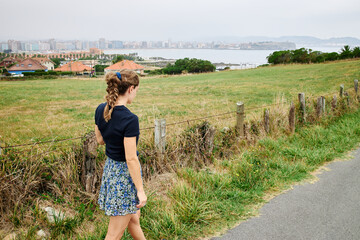 Back view of woman walking side the lawn and sea