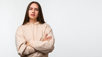 Fototapeta premium Photo of Offended girl posing isolated on white background. Holding hands crossed, looking at camera. Place for ad