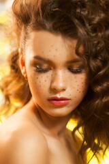 Creative winter makeup with golden snowflakes on her face and wavy hairstyle