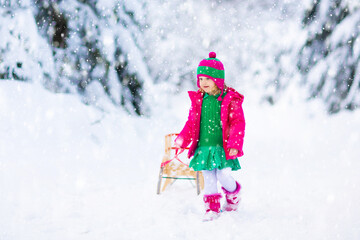 Girl on sled ride. Child sledding. Kid on sledge