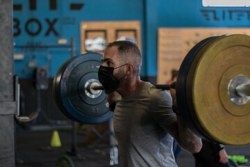 Chico con mascarilla en un gimnasio realizando Cross training