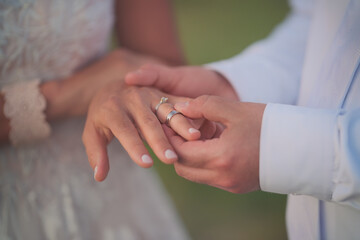 Close-up of a man's hand putting a ring on a woman's hand.