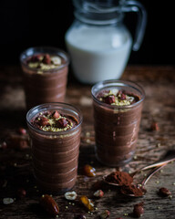 Fototapeta na wymiar Homemade chocolate nutella with nuts in glasses. Milk in a jug. On a wooden background.